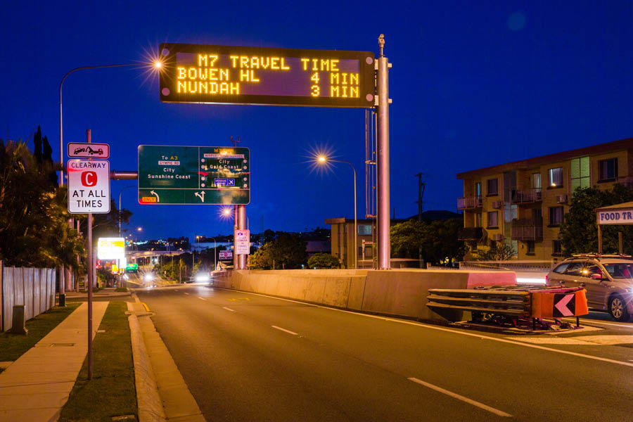 Overhead variable message sign and traffic signals at a suburban intersection at dusk