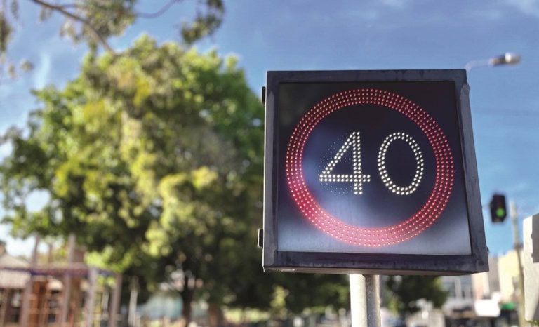 Electronic speed limit sign displaying 40 in red LEDs at a suburban intersection